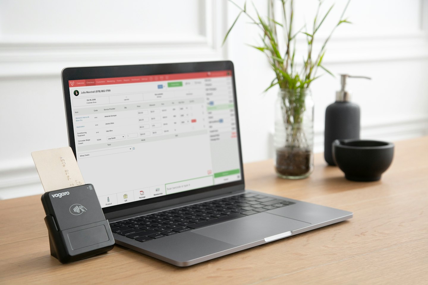 Laptop z oprogramowaniem do planowania i czytnikiem kart kredytowych na biurku.
