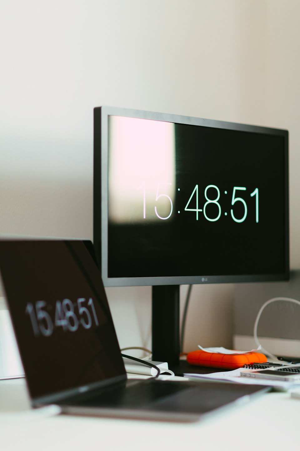 Nowoczesne biurko w biurze z laptopem i monitorem wyświetlającym godzinę.